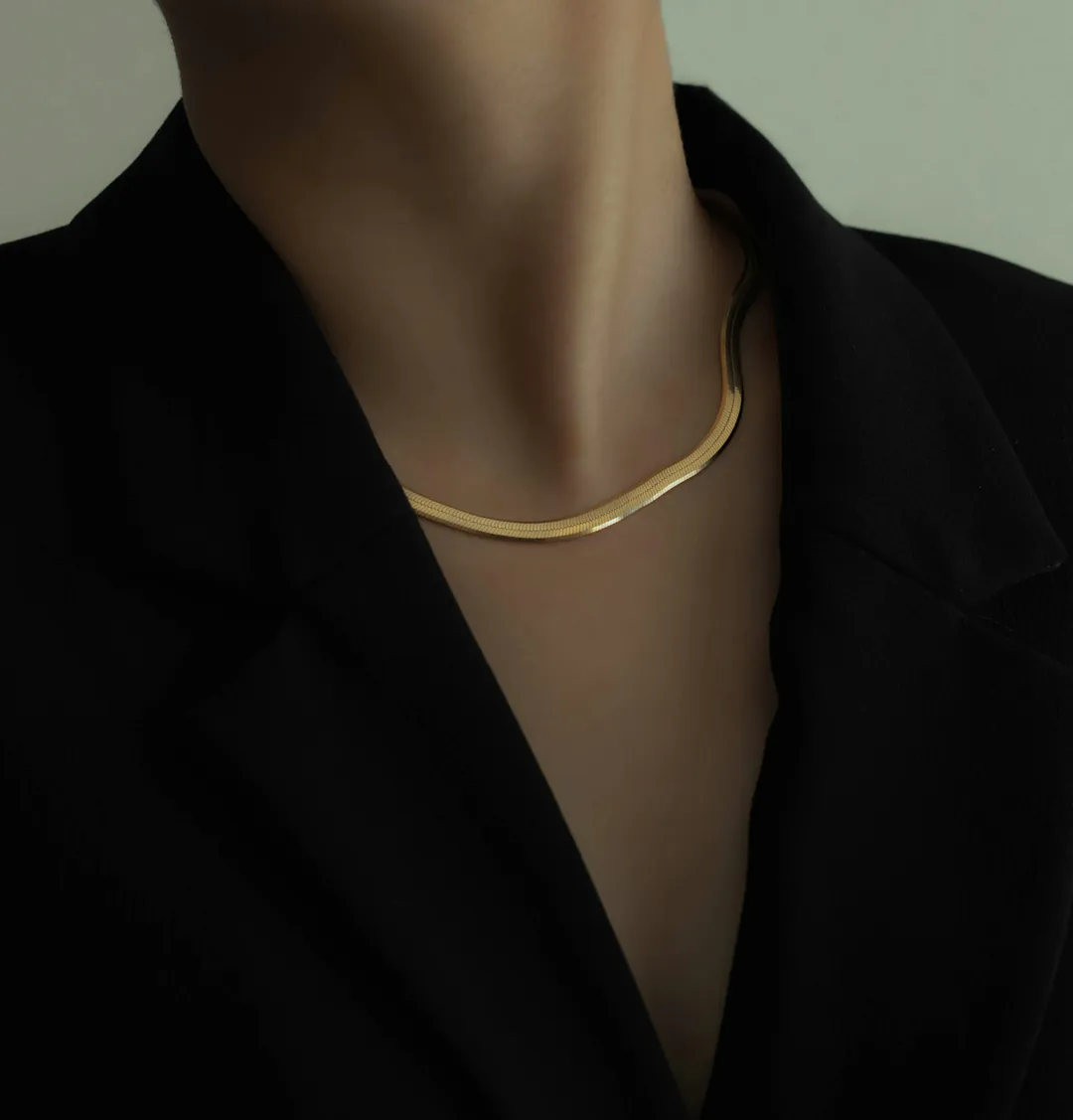Close-up of a fine gold chain necklace worn with a black blazer